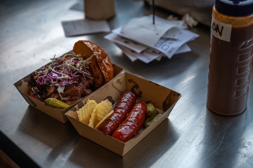 Pulled pork burger with slaw, cheese kranskies and cornichons in serving boxes
